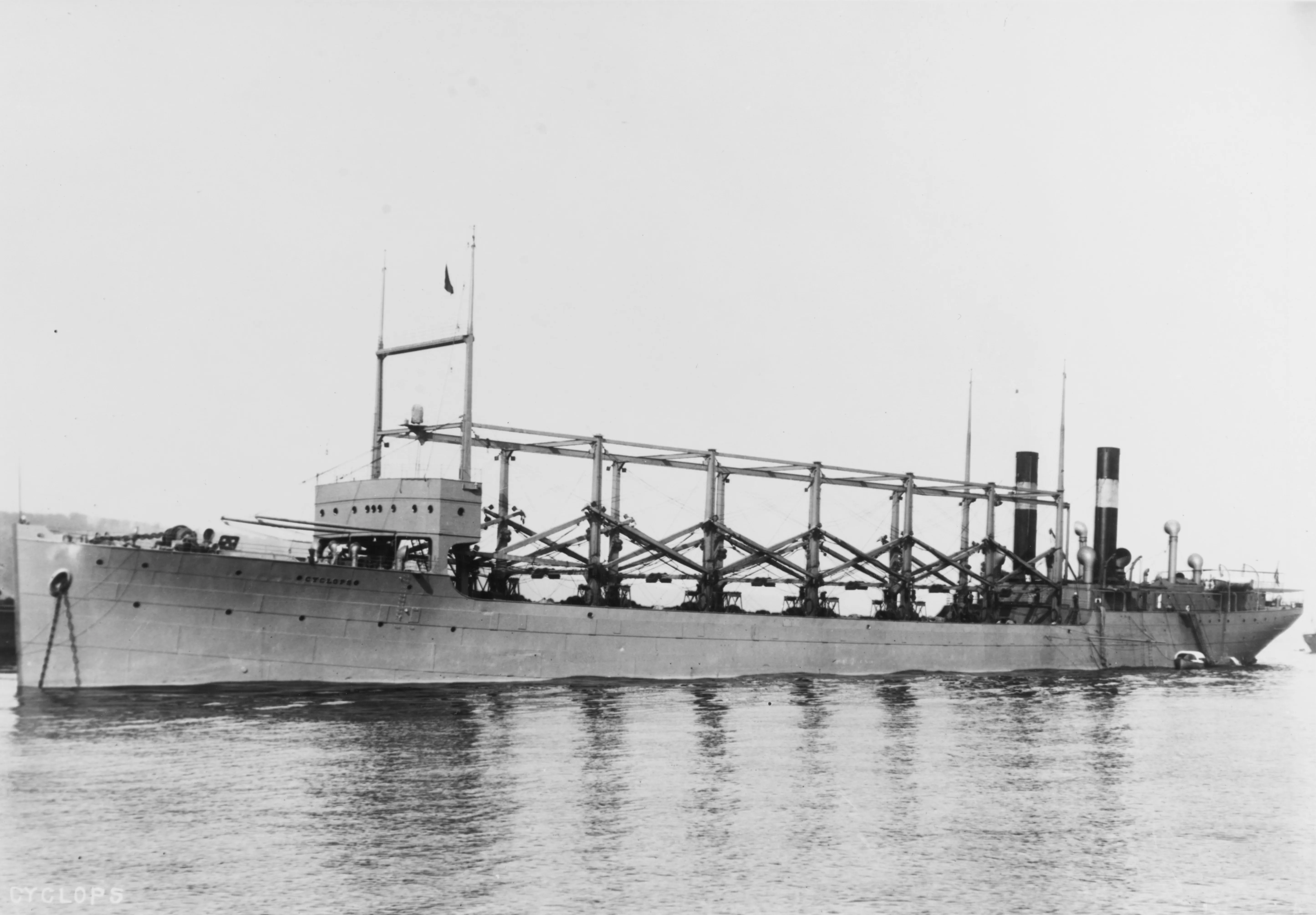 Profile photograph of USS Cyclops, a four-mast collier with a central superstructure, on a river.