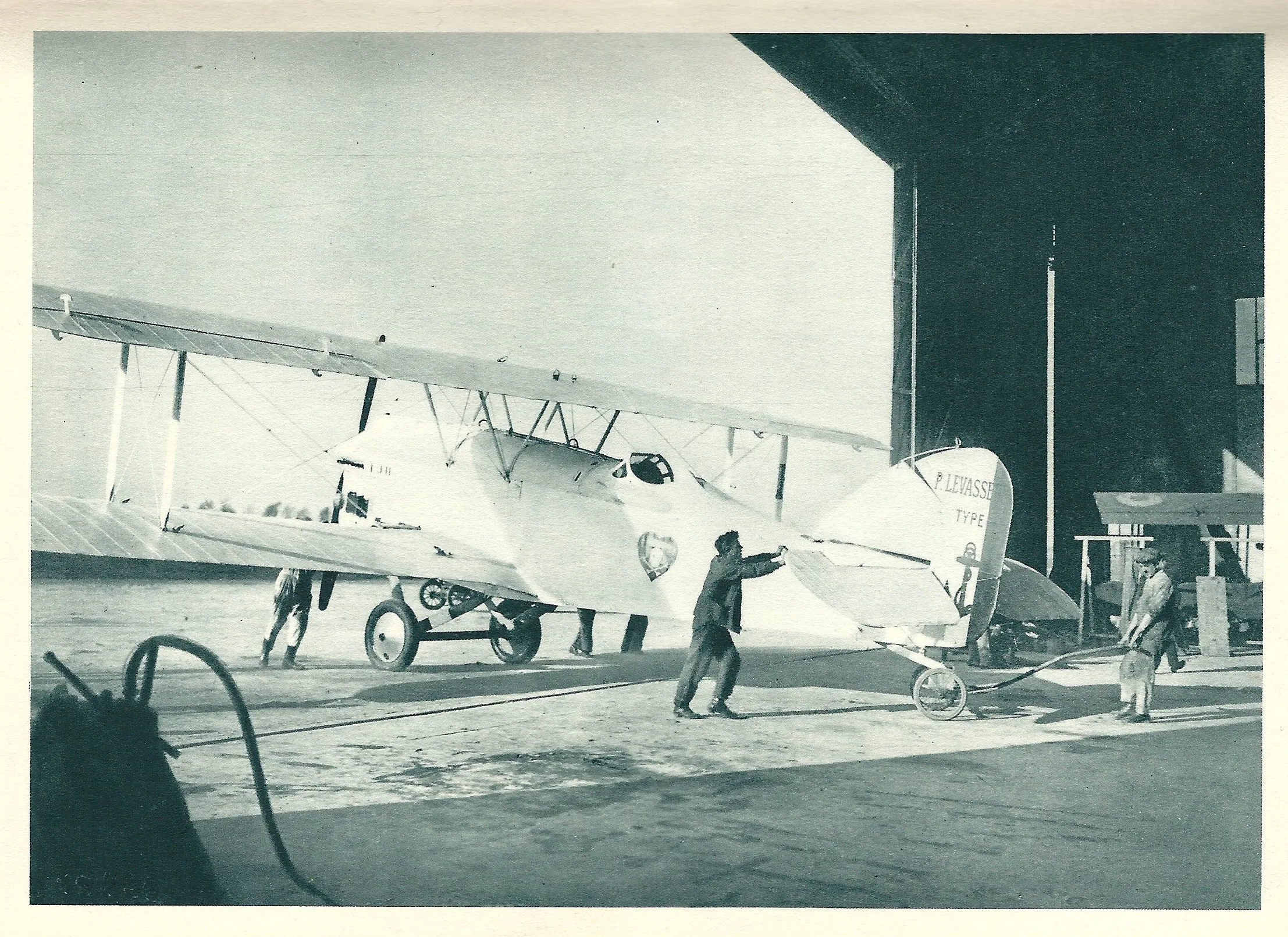 Charles Nungesser standing beside L'Oiseau Blanc, a large white biplane, in a hangar.