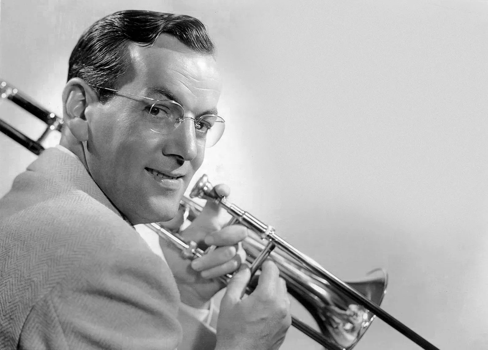 Glenn Miller in suit and tie holding a trombone, photograph c. 1942.